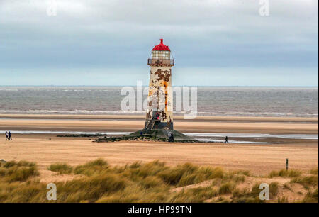 Les gens marchent sur le sable au phare de Talacre sur la plage dans le Nord du Pays de Galles, après un démarrage exceptionnellement doux pour la semaine. Banque D'Images