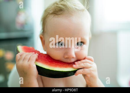 Cute little girl sitting in high chair eating watermelon Banque D'Images