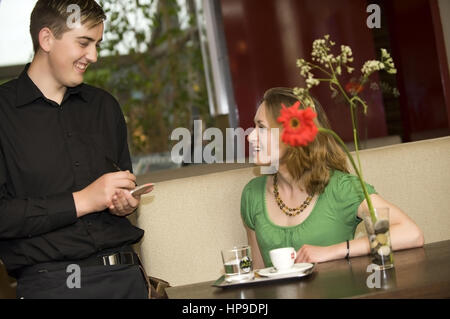 Parution du modèle , Kellner bedient junge Frau im Kaffeehaus - in cafe Banque D'Images