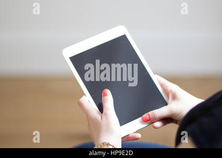 Un caucasian woman with red nails est titulaire d'un iPad blanc Banque D'Images