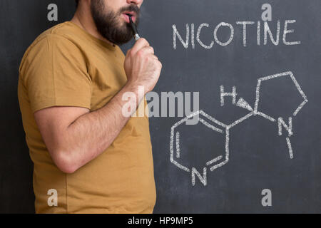 La structure chimique des molécules de nicotine sur tableau noir. Structure chimique de nicotine des cigarettes écrit sur tableau noir avec l'homme à côté de fumeurs choisir Banque D'Images