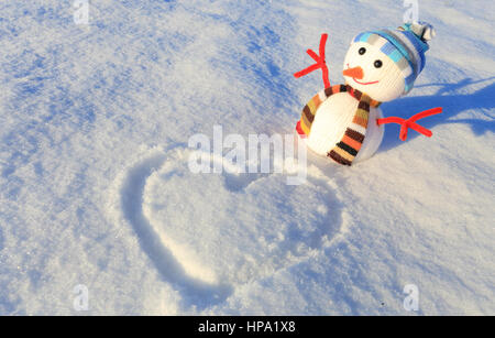 Petit bonhomme de neige sur la neige. Valentines Day belle arrière-plan. Un coeur sur la neige blanche. Banque D'Images