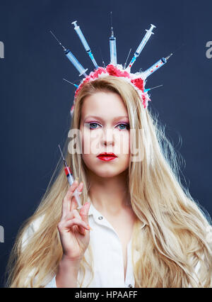 Costume Halloween d'une infirmière folle avec couronne faite de seringues et d'une seringue dans la main Banque D'Images