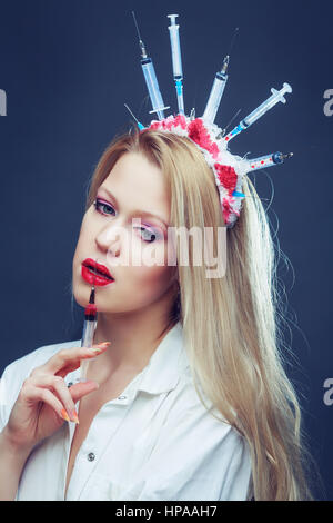 Costume Halloween d'une infirmière folle avec couronne faite de seringues et d'une seringue dans la main Banque D'Images