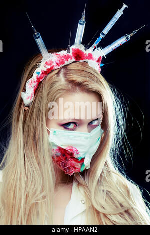 Costume Halloween d'une infirmière folle avec couronne faite de seringues et d'une seringue dans la main Banque D'Images