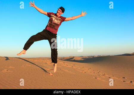 Jeune homme sautant joyeusement dans l'air, Désert du Namib, Swakopmund, Langstrand, Erongo, Namibie Région Banque D'Images