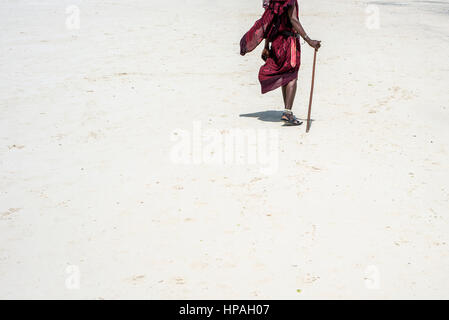 Un homme marche Masai sur une plage de Nungwi, Zanzibar, Tanzanie Banque D'Images