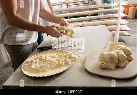 Avec la pâte de travail masculins baker, pan avec la farine et du pain sur peel en bois en premier plan Banque D'Images