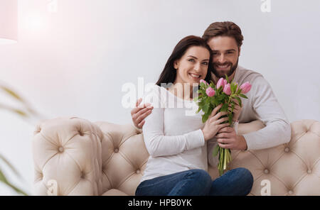 Heureux couple. Agréable agréable plaisir couple smiling and looking at you tandis que holding Flowers Banque D'Images
