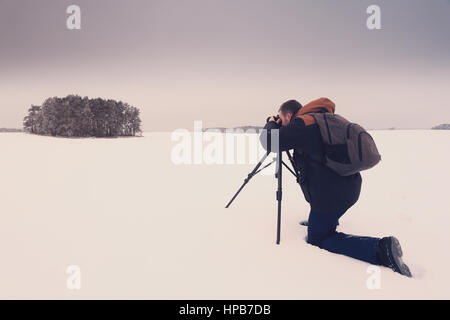 Photographe de prendre une photo. L'homme avec l'appareil photo sur la neige paysage faire photo. Photographe sur fond de neige. Banque D'Images