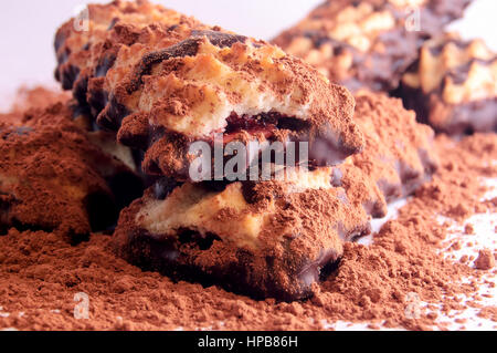 Pile de biscuit avec de la confiture et du chocolat cerise sur la dispersion de la poudre de cacao sur fond blanc. Banque D'Images