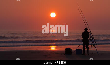 La capture d'un coucher du soleil sur la plage de Trecco Bay près de Porthcawl au Pays de Galles. Seul l'espoir d'un pêcheur attraper que les couchers de soleil Banque D'Images