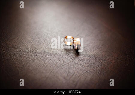Anneaux de mariage d'or sur fond de cuir brun sur la lumière naturelle. Banque D'Images