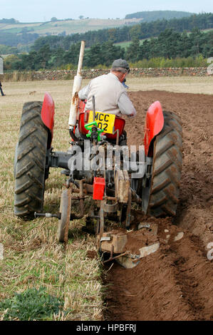 Un paysan sur un tracteur vintage avec un sillon de labour 2 charrue à un concours de labour, Cumbria, Royaume-Uni. Banque D'Images