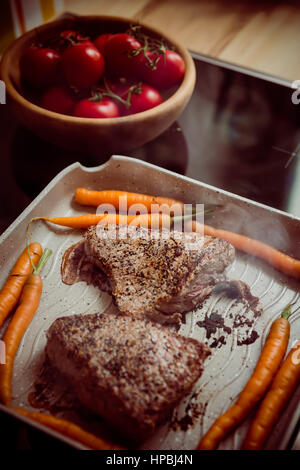 Steaks de boeuf frais avec les carottes dans une poêle à frire sur table close up.Slise de steak. Selective focus Banque D'Images