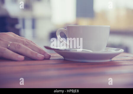 Main d'un jeune homme sur une table en bois dans le café avec une tasse de café dans la main de détente calme,piscine d'arrière-plan flou de la posture Banque D'Images