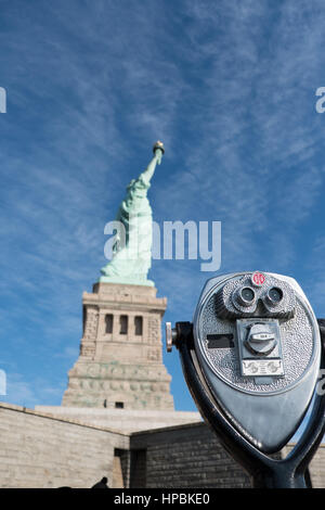 Visionneuse de tour jumelles dans l'accent, de la Statue de la liberté à l'arrière-plan flou, faible profondeur de champ. Statue de la liberté à profil sur Liberty Island Banque D'Images