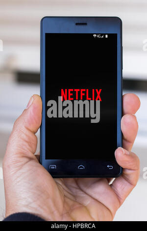 Close-up of man's hand holding cell avec netflix logo sur écran. (Editorial uniquement) Banque D'Images