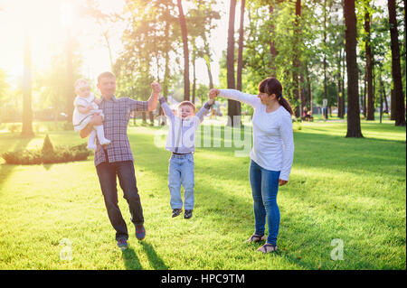 Les jeunes parents avec enfants à pied dans le parc d'été Banque D'Images