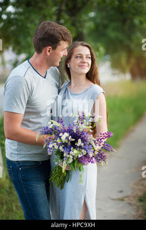 Jeune couple dans l'amour avec un bouquet de fleurs sur un fond de la voie Banque D'Images