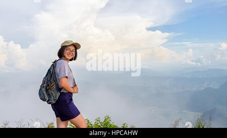 Teens girl randonneur porter une casquette et des lunettes avec sac à dos est debout et souriant joyeusement sur la haute montagne au point panoramique de Phu Chi Fa Forest Park Banque D'Images