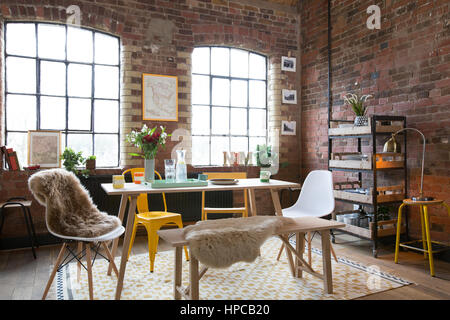 Une salle à manger dans un style loft avec des murs en briques et de grandes fenêtres Banque D'Images