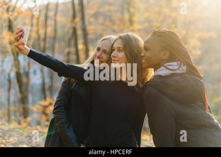 Trois beaux selfies woman in autumn park. Jolies filles avec différentes couleurs de peau Banque D'Images