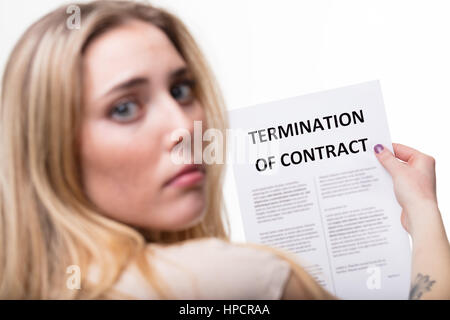 Cessation d'emploi concept, l'accent sur une cessation d'emploi document avec une triste femme blonde inquiète hors focus trouver à votre Banque D'Images