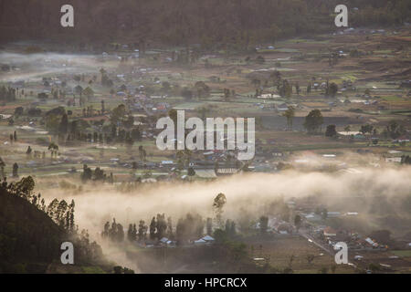 Lever de brume sur la vallée avec des villages situés dans la caldeira du volcan Batur à Bali, Indonésie Banque D'Images