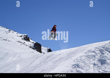 Snowboarder sautant dans parc acrobatique à ski sur sun journée d'hiver. Montagnes du Caucase, région Chelyabinsk. Banque D'Images