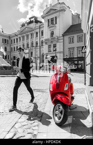 Scooter rouge debout sur la rue en noir et blanc de la vieille ville de Vilnius, Lituanie Banque D'Images