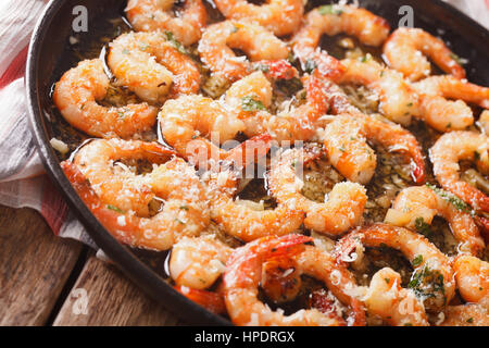 Crevettes frites dans une sauce à l'ail avec le parmesan et les herbes gros plan sur une poêle. L'horizontale Banque D'Images