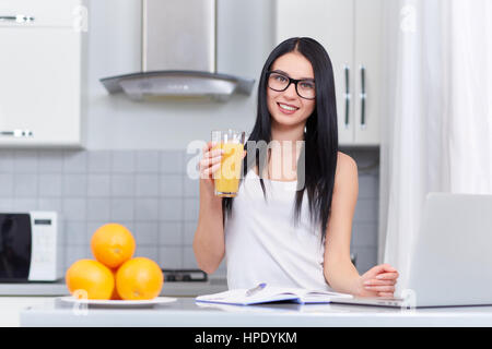 Fille brune dans les verres d'étudier, de l'écriture accueil tâche en cuisine et l'aide de lap top. Matin d'étudiants et de personnes avec succès. Près de sur la table books Banque D'Images