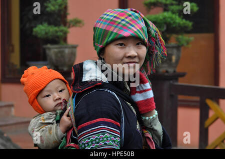 SA PA - février 23, 2013 : une femme Hmong non identifié portant son enfant dans son porte-bébé dans le nord du Vietnam. Les Hmongs sont une des plus grandes Banque D'Images