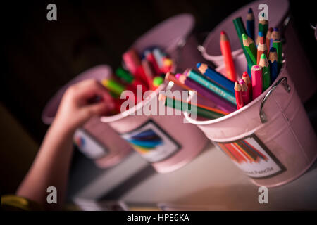 La main de l'enfant de l'école le choix d'un crayon de couleur à partir de petits pink bucket selective focus Banque D'Images