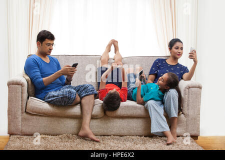 À l'aide de la famille des téléphones mobiles et des tablettes numériques dans la salle de séjour Banque D'Images