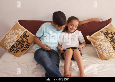 Brother and sister using digital tablet in bedroom Banque D'Images