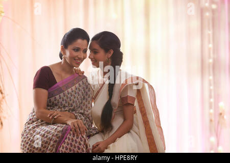 Smiling teenage daughter à sari chuchoter à mère Banque D'Images