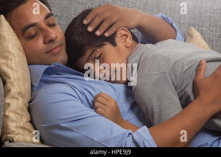 Père et fils dormir sur canapé Banque D'Images