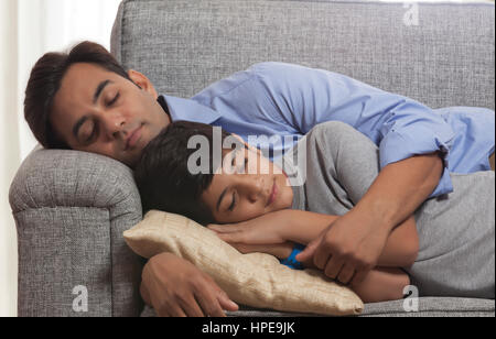 Fatigué père et fils dormir ensemble sur le canapé à la maison Banque D'Images