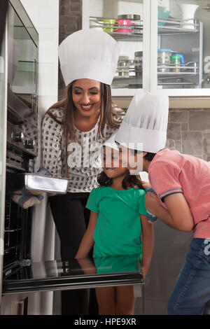 Mère avec la fille et le fils portant des chefs hat et la cuisson des gâteaux dans la cuisine Banque D'Images