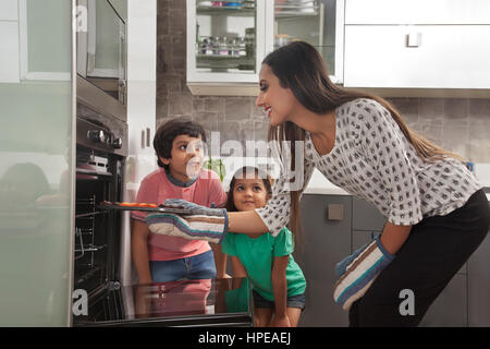 Maman avec ses deux enfants la cuisson au four Banque D'Images