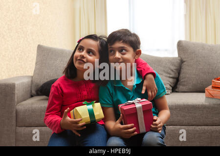 Brother and sister holding présente dans la salle de séjour Banque D'Images