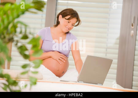 Schwangere Frau modèle libéré , mit liegt am portable Bett - femme enceinte using laptop Banque D'Images