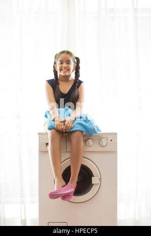 Jeune fille assise sur un lave-linge Banque D'Images