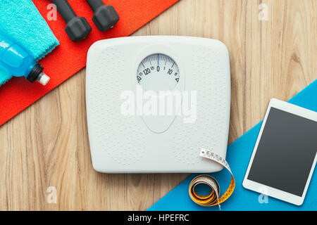 L'échelle de poids, tablette numérique et l'équipement d'entraînement sportif sur une table, la perte de poids et un mode de vie sain concept, mise à plat Banque D'Images