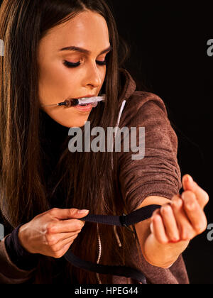 Aiguille de l'héroïne dans la main de femme toxicomane les stupéfiants . Junkie avec seringue sur table sale. Questions et Sossial portrait close up. Fond noir comme le symbole o Banque D'Images