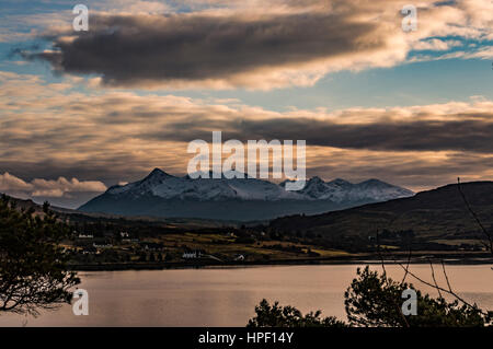 La Black Cuillin Hills mountain de 'la' à Portree, Isle of Skye, Scotland. Arbres en premier plan et ciel dramatique, éclairé par le soleil l'après-midi. Banque D'Images