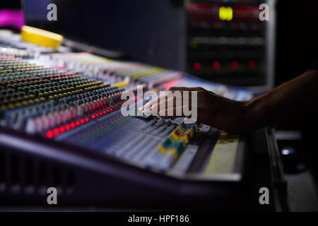 Sonorisateur de travailler sur la console de mixage. mains sur les sliders. Banque D'Images