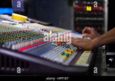Sonorisateur de travailler sur la console de mixage. mains sur les sliders. Banque D'Images